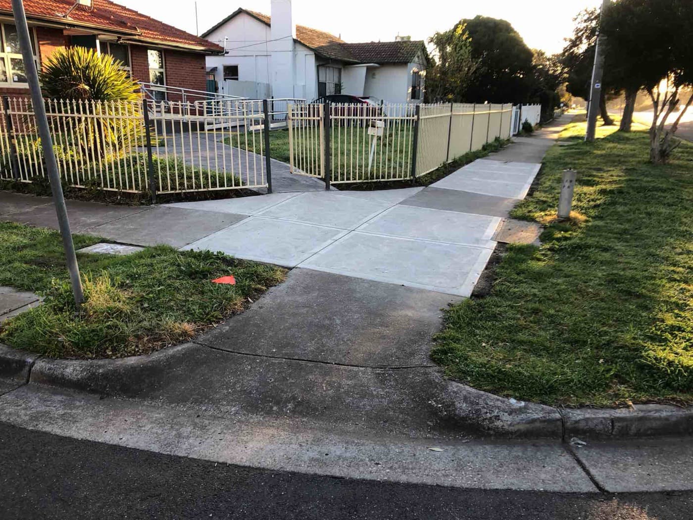 Completed footpath crossing panels at a street corner in warm light
